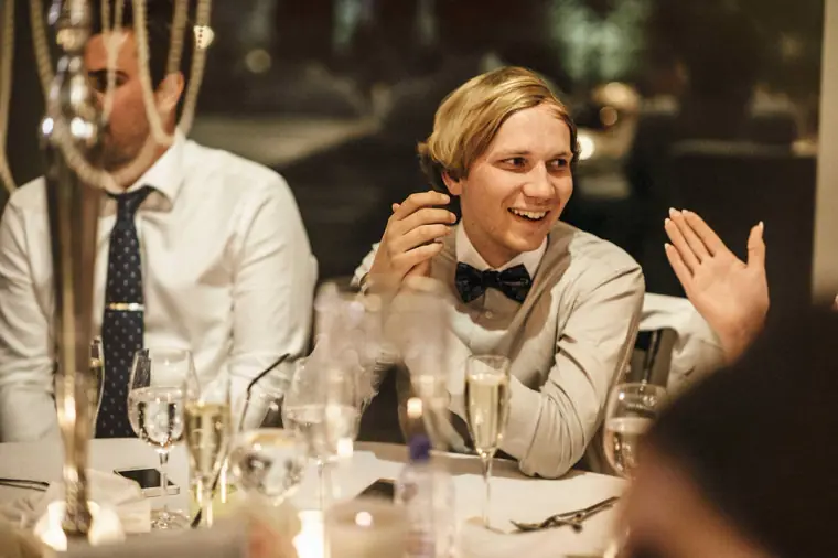 Guest in a bow tie laughing and gesturing at the reception table