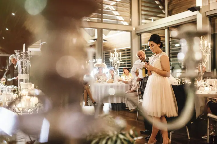 Bridesmaid in a cream dress giving a speech in the reception hall