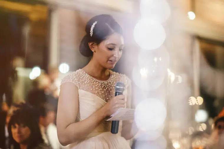 Bride reading her own speech into a microphone at the reception