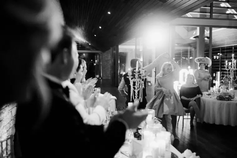 Black-and-white view of guests applauding in the candlelit reception room