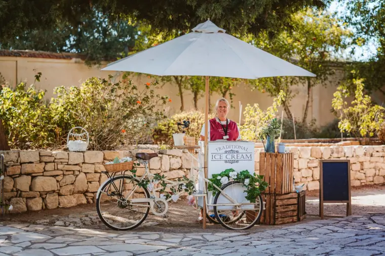 Drinks cart with a white parasol and vintage bicycle in a stone-walled courtyard