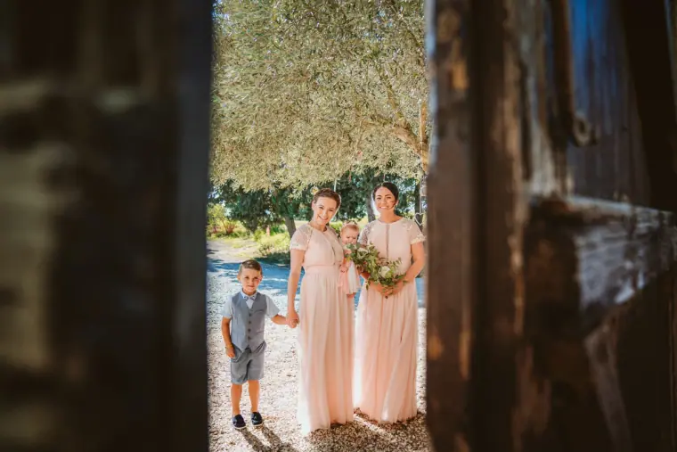 Bridesmaids in blush dresses and a page boy waiting in a doorway