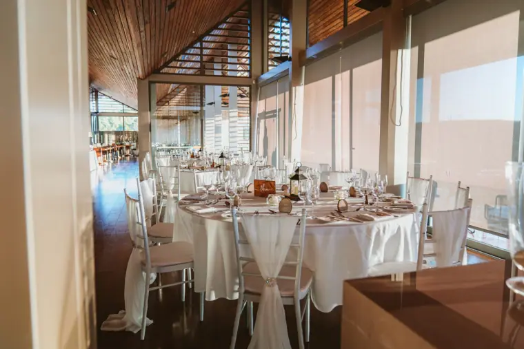 Reception room with white tables and chairs by tall windows at Minthis Hills
