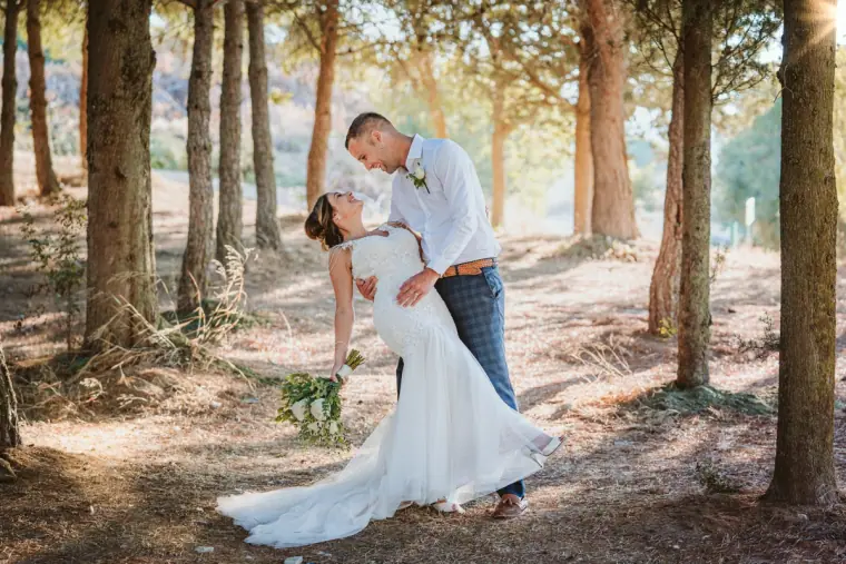 Groom dipping the bride for a kiss among tall pine trees