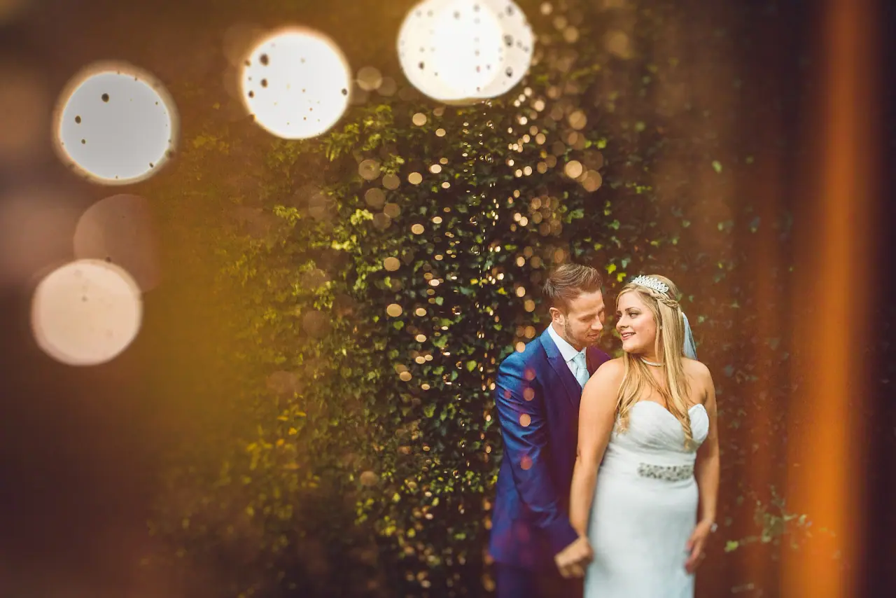 Lyndsay and Thomas embracing beside sparkling bokeh lights at Balmer Lawn Hotel, New Forest