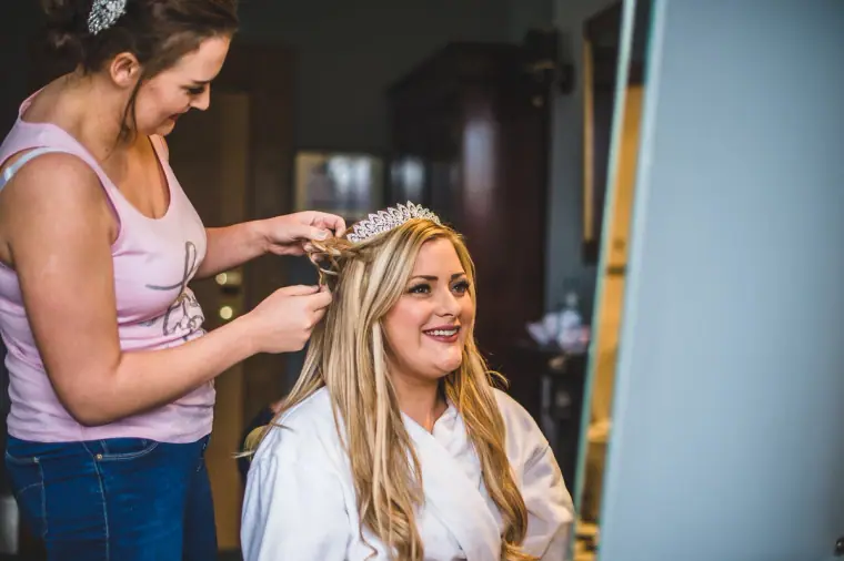 Bride laughing as a bridesmaid places a tiara in her hair