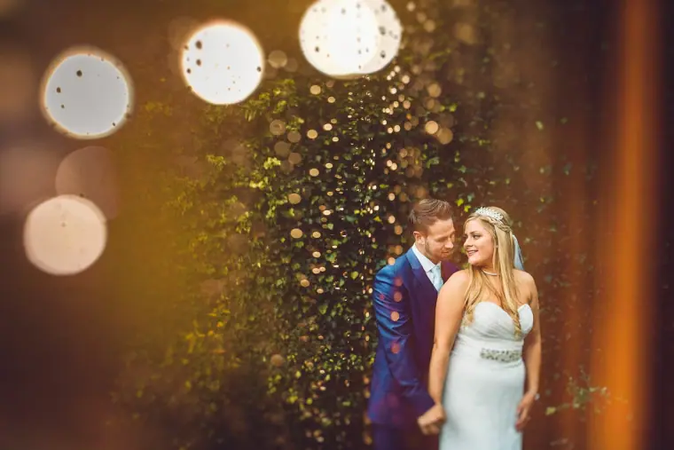 Bride and groom side by side, framed by glittering bokeh lights at Balmer Lawn Hotel