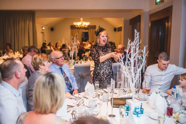 Guest giving a speech among tables with white branch centrepieces