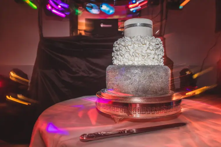 Two-tier silver and white wedding cake under coloured disco lights