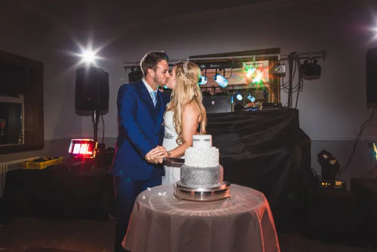 Lyndsay and Thomas kissing as they cut their silver wedding cake