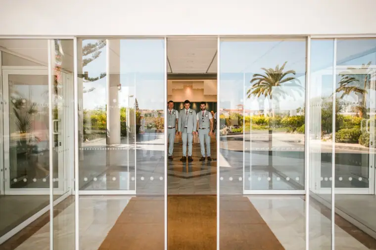 Groom and groomsmen walking through the hotel's glass entrance doors