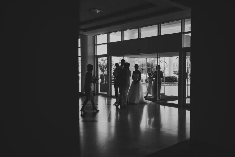 Silhouettes of the bridal party in the dark hotel lobby against bright doors