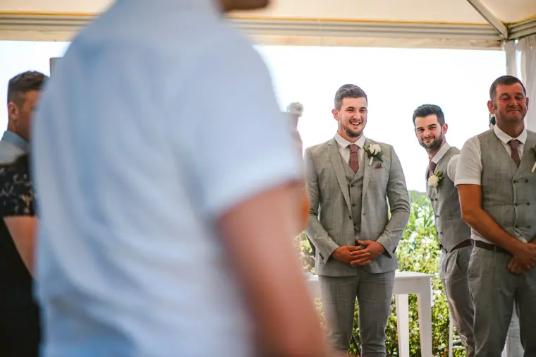 Groom and groomsmen waiting under the white canopy as the bride approaches