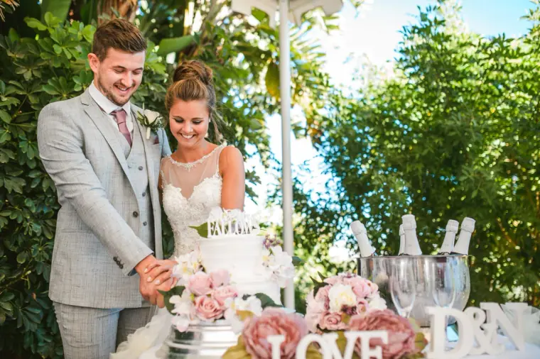 Bride and groom cutting their cake beside the LOVE letters and champagne