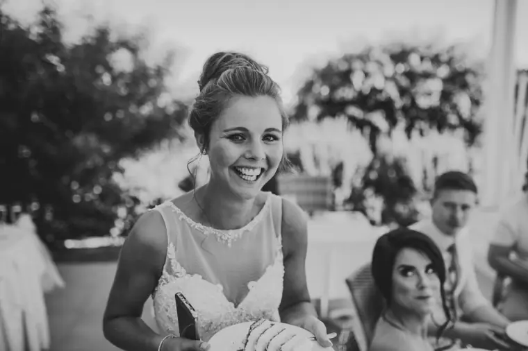 Black-and-white shot of the bride beaming at the reception table