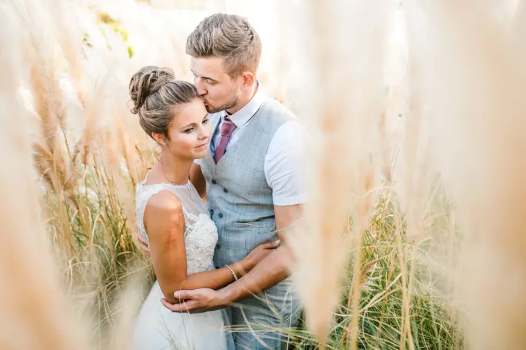 Naomi and Dale embracing among pampas grass in golden light at Nissi Beach Resort