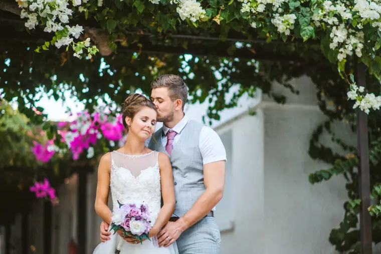 Bride and groom beneath white bougainvillea and pink flowers