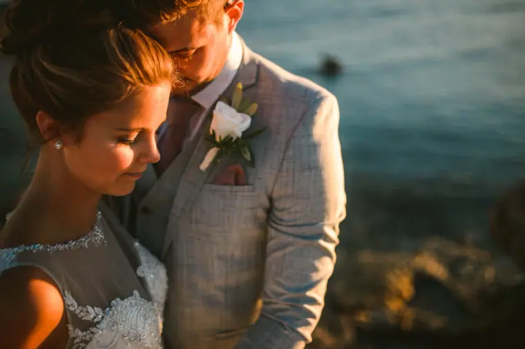Close-up of the bride resting against her groom in warm evening light