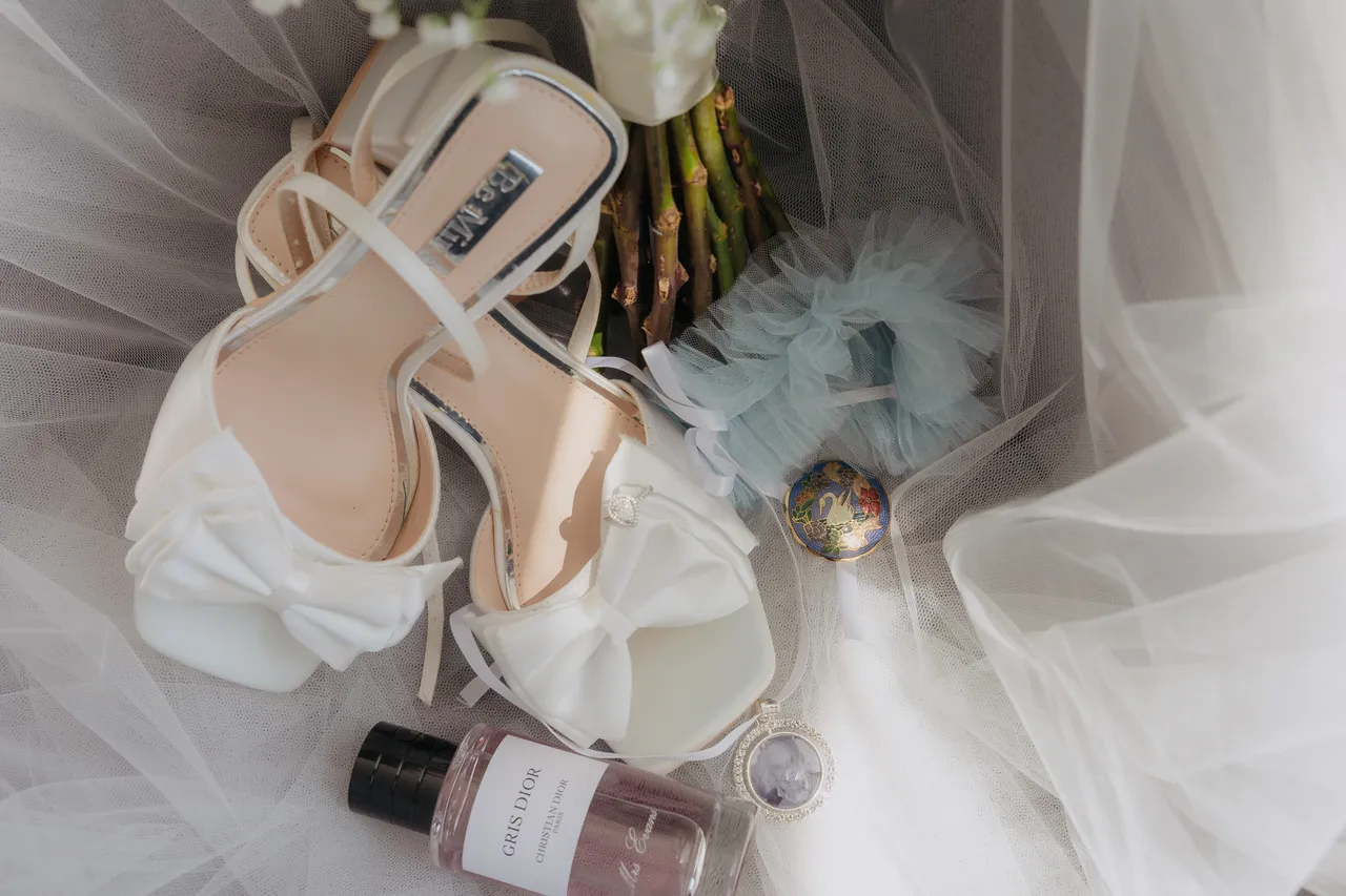Bridal shoes, perfume and jewellery laid out on a tulle veil