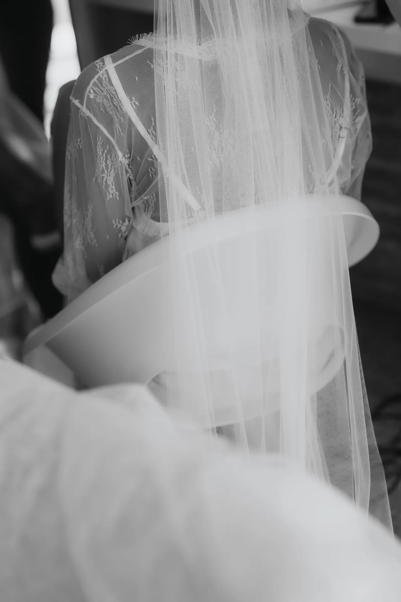 Black-and-white detail of the bride's veil and lace robe