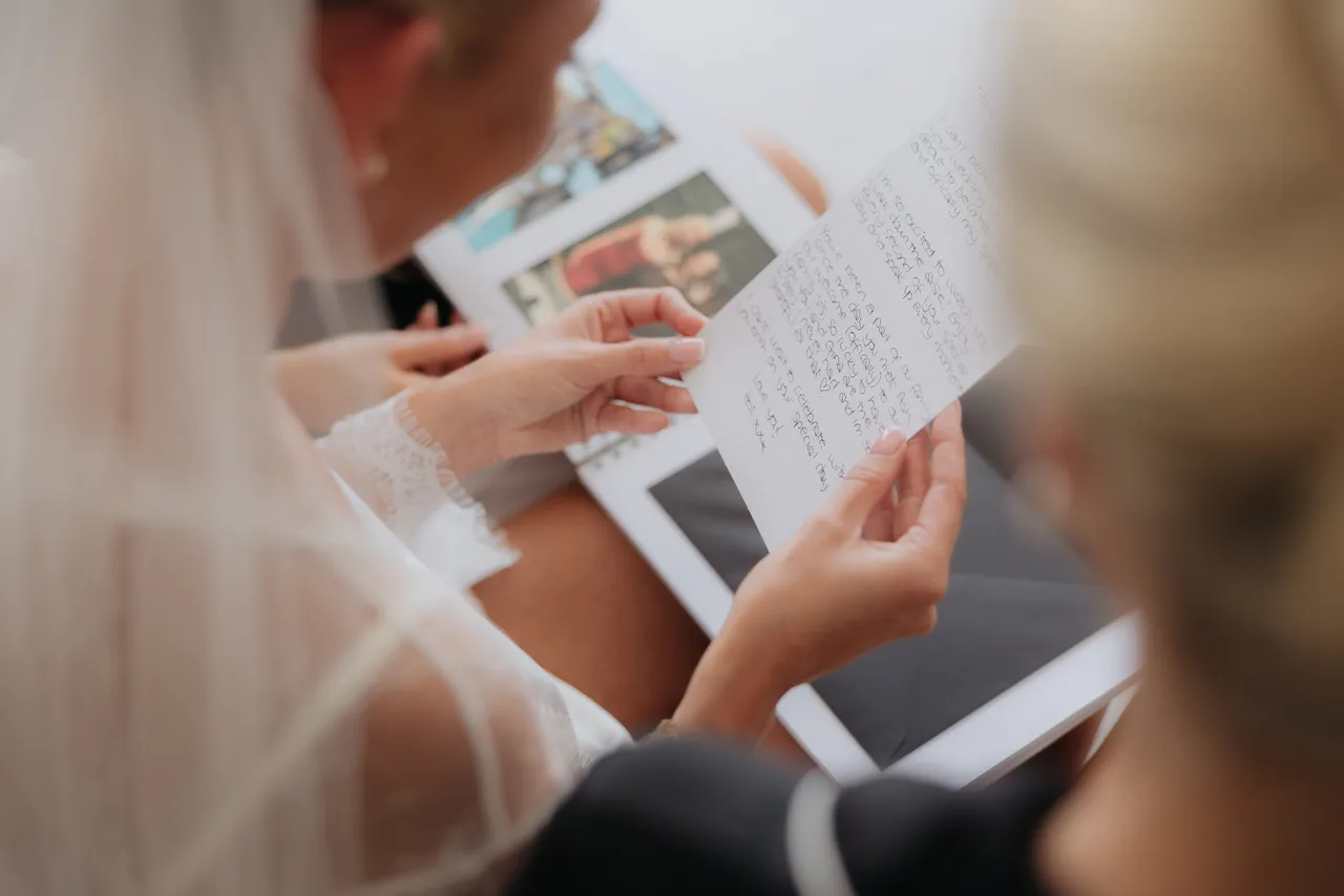 Bride reading a handwritten letter tucked inside a photo album