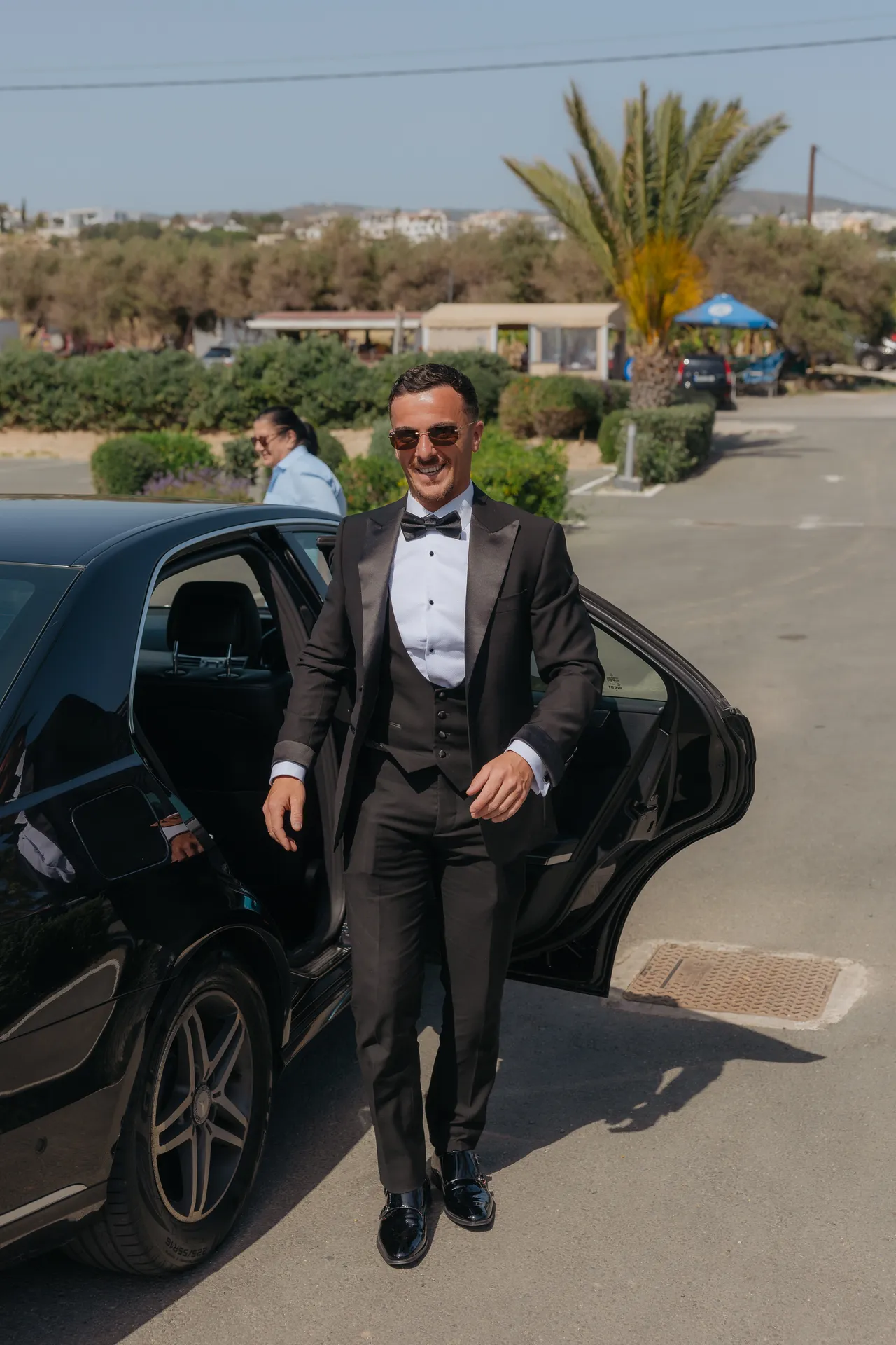 Ashley in a black tuxedo stepping out of a car on arrival at Alassos