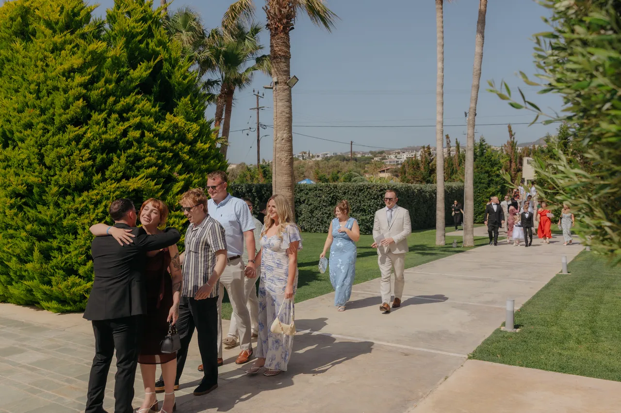 Guests greeting each other on a palm-lined garden path at Alassos