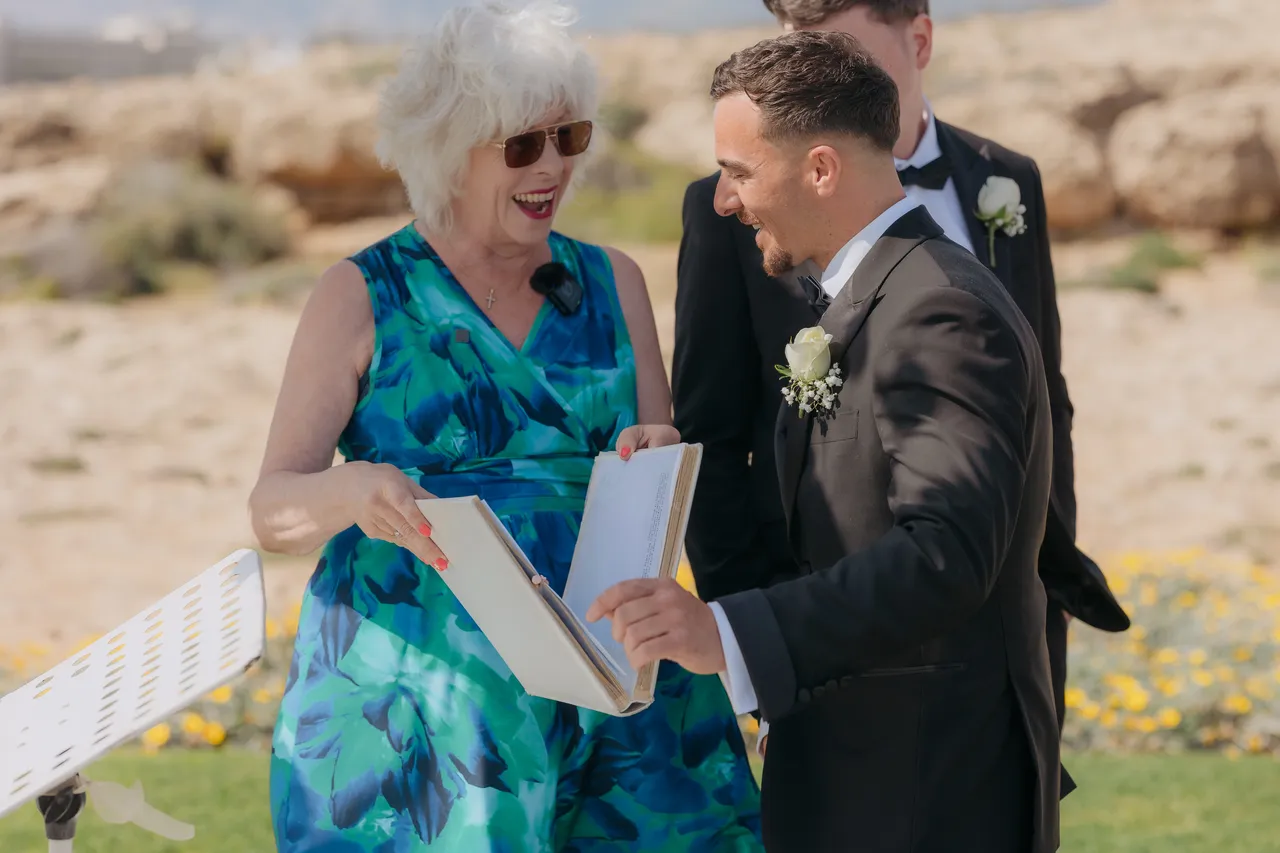 Celebrant in a blue floral dress laughing with the groom before the ceremony