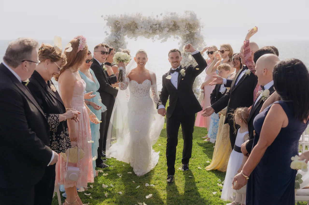 Bride and groom walking back up the aisle as guests cheer