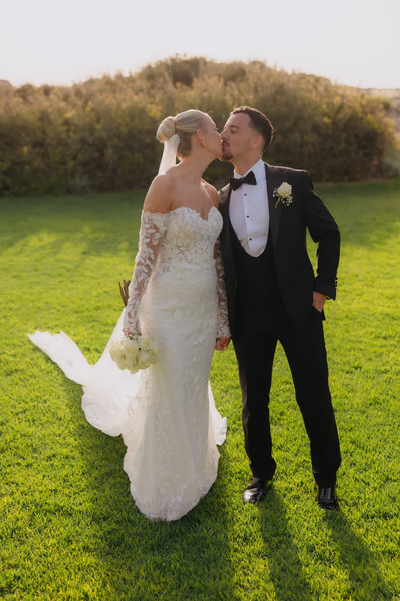 Olivia and Ashley kissing on a sunlit lawn in the evening light