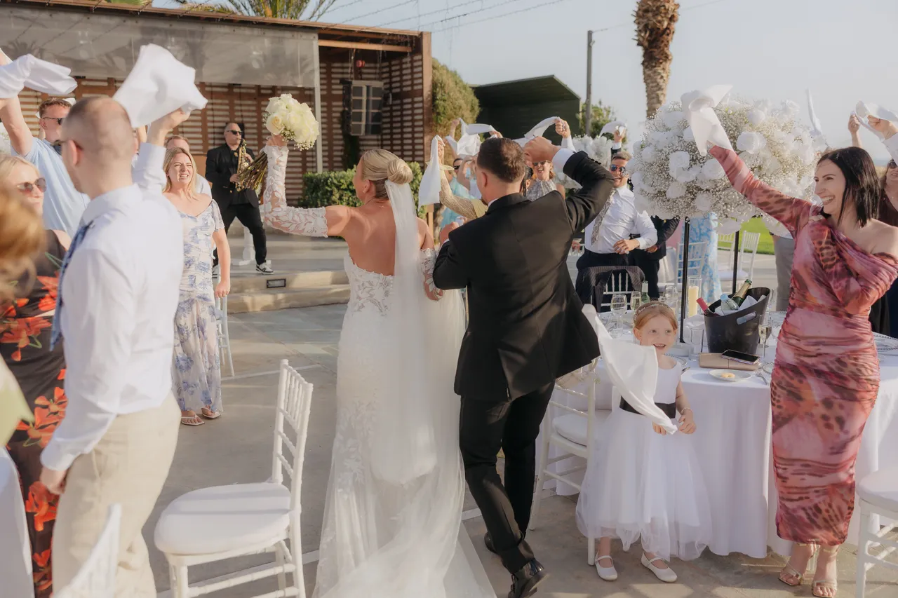 Guests waving napkins as the newlyweds dance into the reception