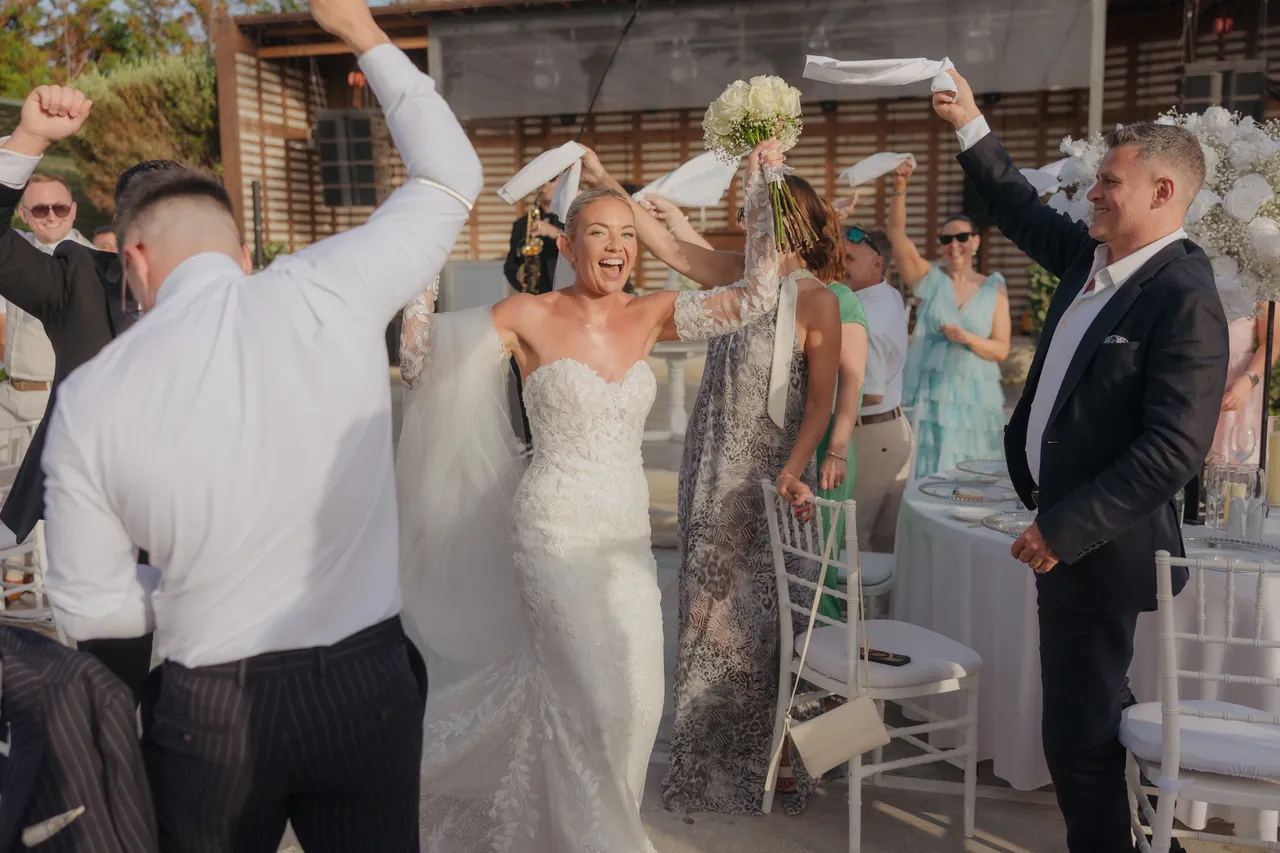 Bride and groom entering the reception with arms raised as guests cheer