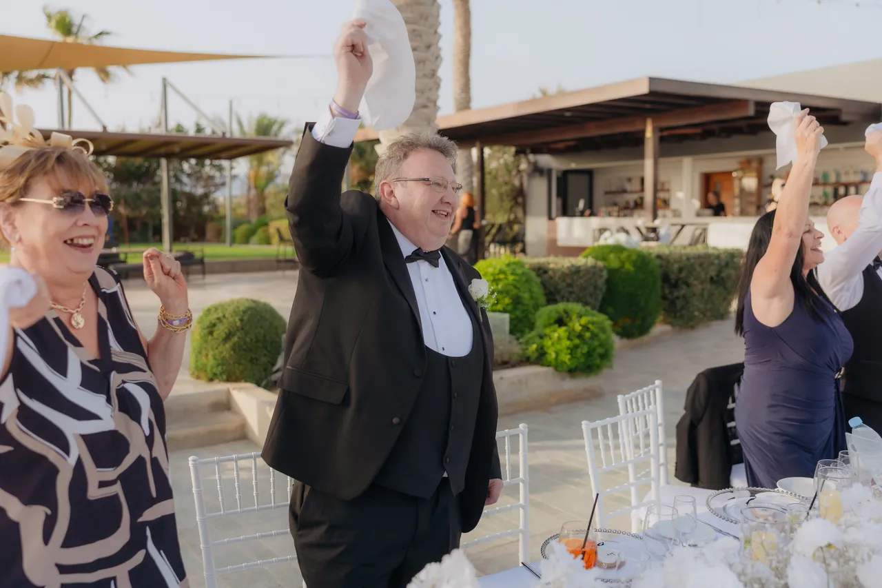 Guests cheering and waving napkins overhead at the reception