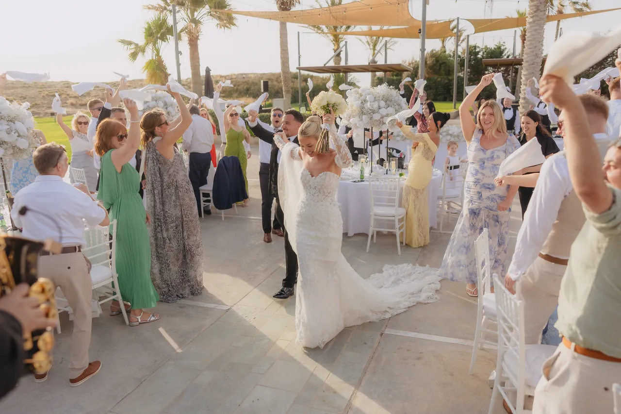 Bride walking between the reception tables as guests wave napkins overhead