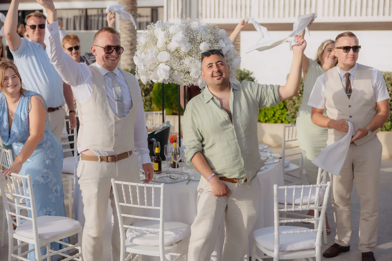 Guests cheering and waving napkins as the newlyweds arrive