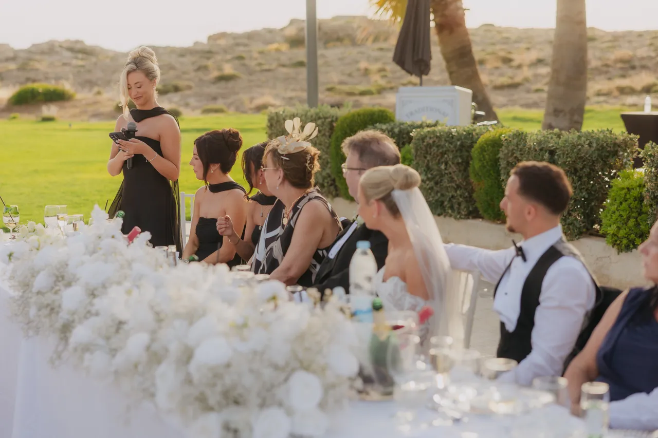Guests at the top table listening to a speech, sea dunes behind