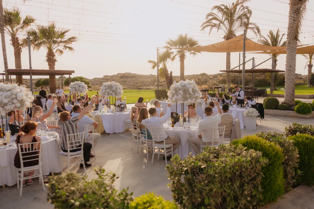 Guests standing for a toast across the palm-fringed reception terrace