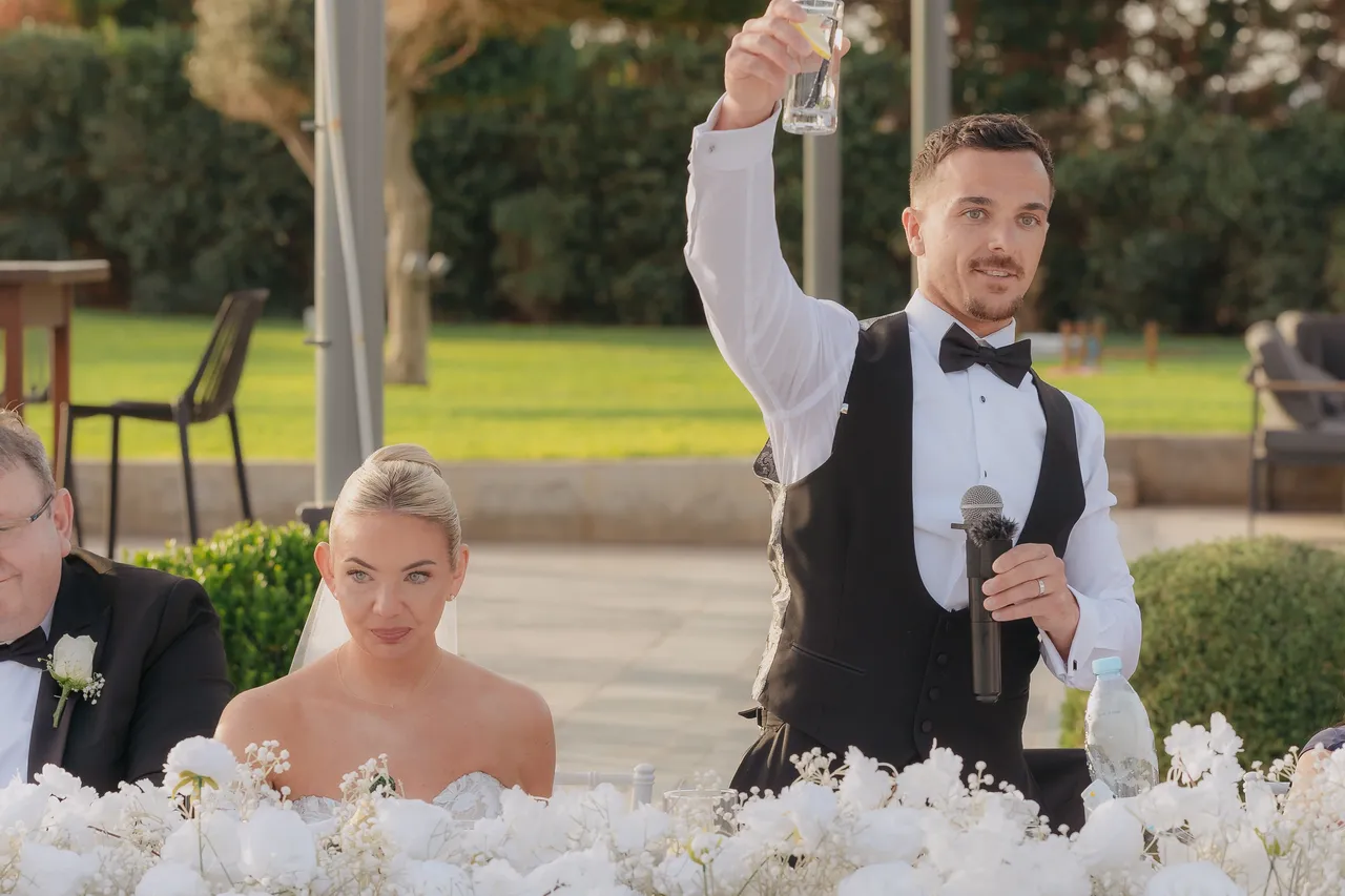 Groom raising his glass in a toast at the end of his speech