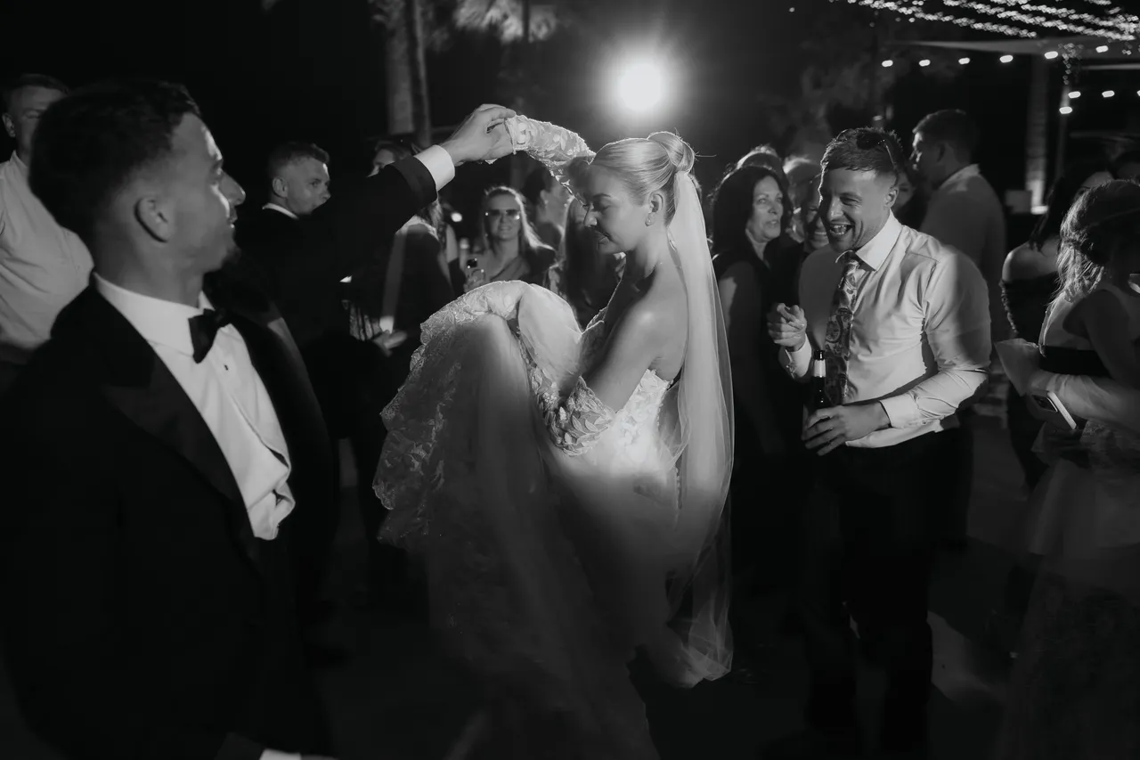 Black-and-white photo of the newlyweds dancing surrounded by guests