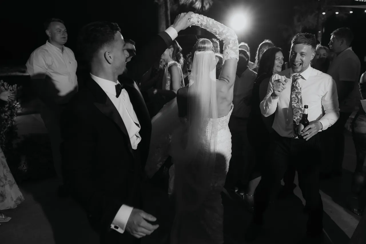 Black-and-white photo of the groom twirling the bride on the dance floor