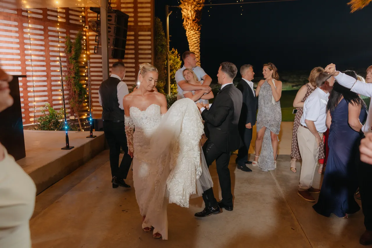 Bride lifting her train as she dances beside the groom