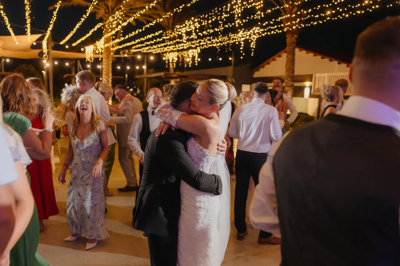 Groom hugging a guest on the busy dance floor