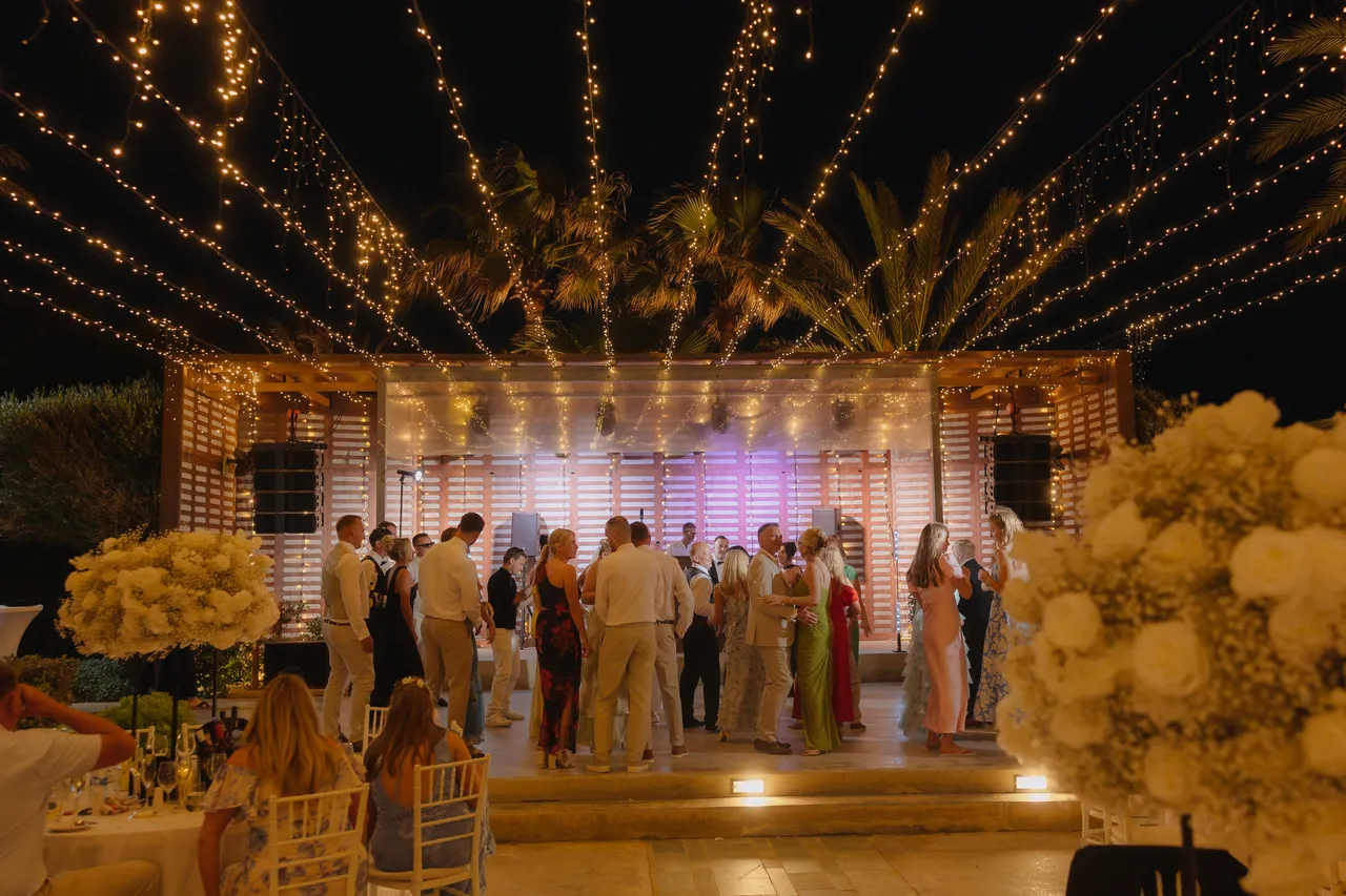 Wide view of the dance floor beneath a canopy of fairy lights at Alassos