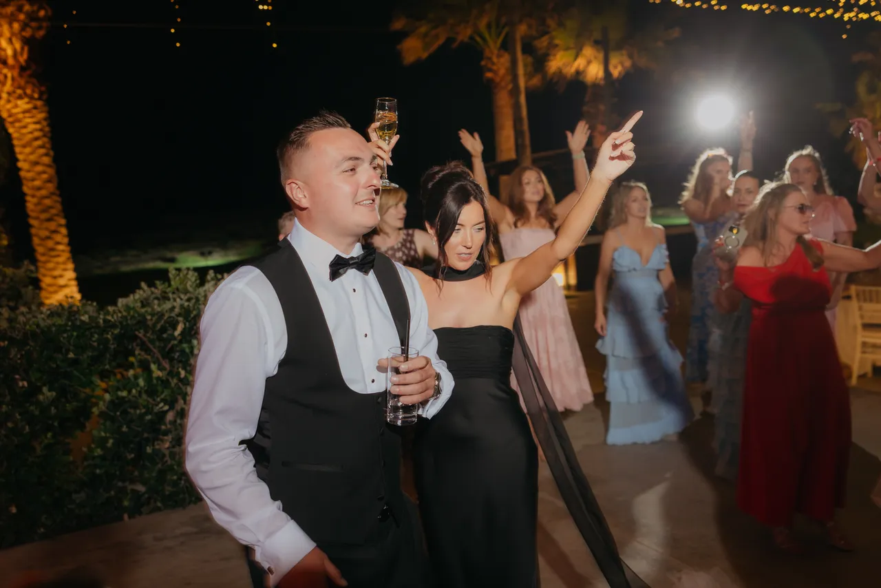 Guests dancing and pointing on the dance floor at night