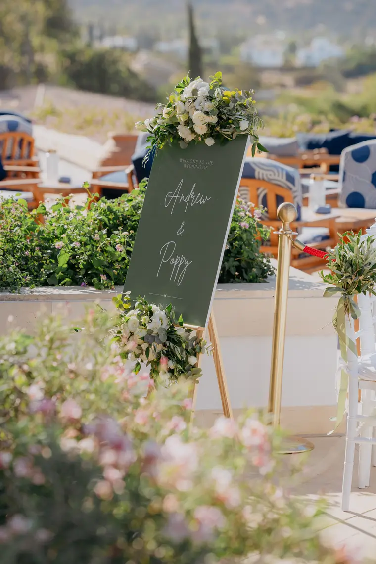 Green welcome sign dressed with white roses beside the ceremony terrace