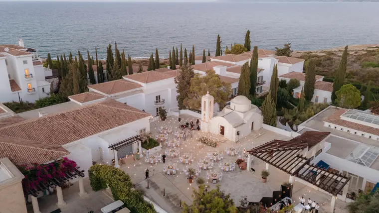 Aerial view of Anassa's whitewashed buildings, chapel and reception courtyard by the sea