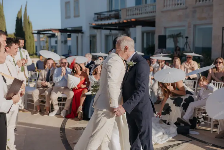 Older guest embracing the groom after the ceremony as others applaud