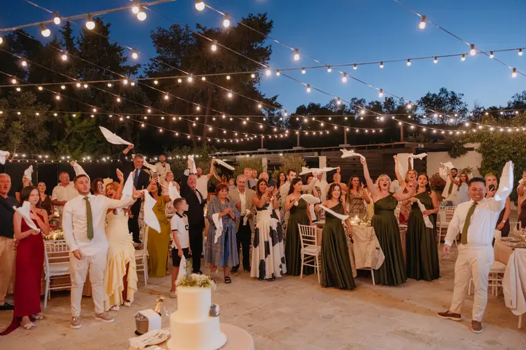 Crowd of guests waving napkins around the dance floor at dusk