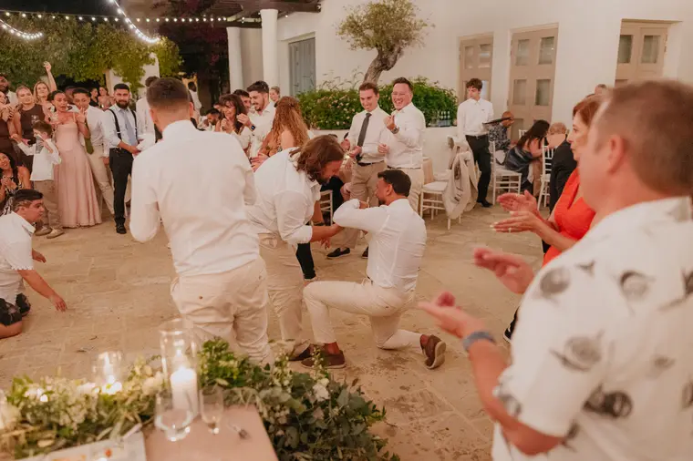Guests clapping as a man kneels mid-dance on the dance floor