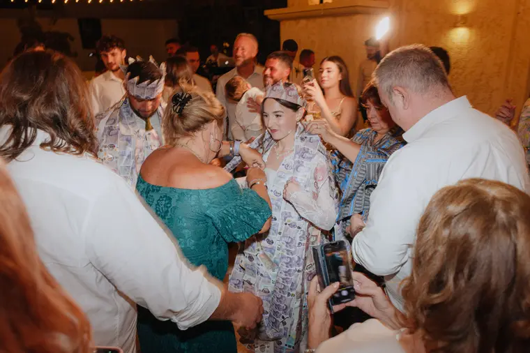 Poppy wrapped in banknotes during the money dance, guests gathered round